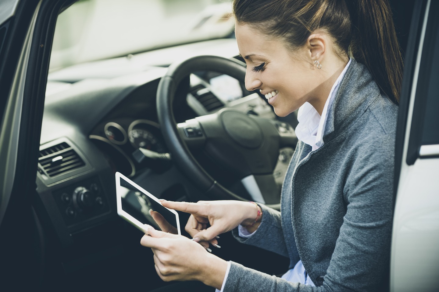 Smiling woman in a car with tablet